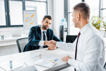 Obraz premium selective focus of businessman shaking hands with coworker in modern office