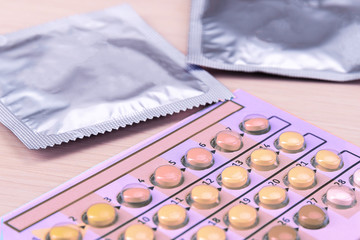 Birth control pills and condoms in package on light background.Concept of choosing method of...
