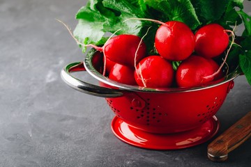 Large bunch of raw fresh garden radish  in red colander