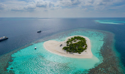 Aerial panoramic view on heart shaped tropical island in blue sea at Maldives background