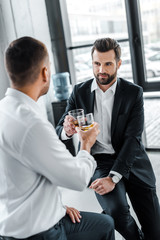 bearded businessman toasting with glass of whiskey with colleague