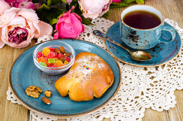 Fresh bun and cup of tea on wooden table for breakfast