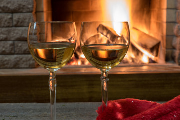 Cozy scene before fireplace with two glasses of wine.