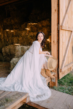 Bride In Cowboy Style Sits On Threshold Of Hayloft