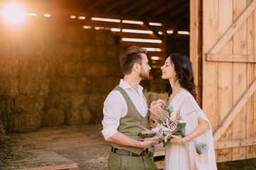 lovers in cowboy style stand near hayloft on ranch