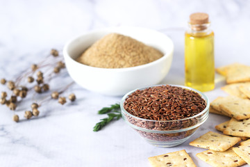 Flax seeds, flax flour, butter and crackers with sprouts and flax bolls on a light background.