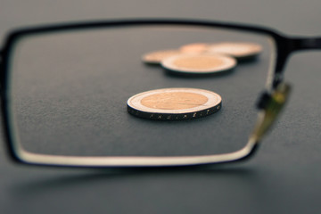 Low financial status concept with eyeglasses and euro coins on a black background