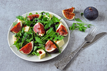 Fresh juicy salad with figs, arugula and white cheese. Healthy colorful fitness salad. Superfoods