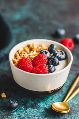 Vegetarian breakfast, a bowl with organic granola, fresh raspberries and blueberries and coconut yoghurt.