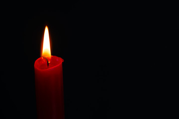 Red candle on a black background.