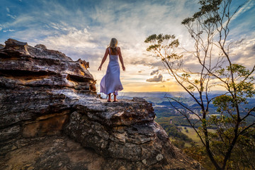 Standing on a rock  with dress blowing in the wind she dreams - Powered by Adobe
