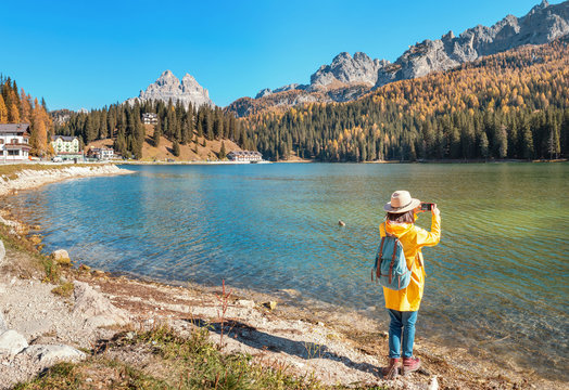 Traveler Woman use mobile phone to take amazing photos of a Misurina mountains lake