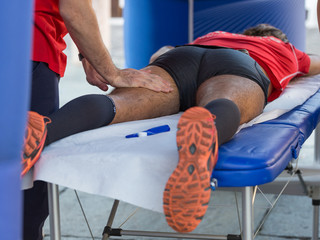 Athlete lying on a Bed while having Legs Massaged after a Physical Sports Workout