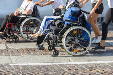 Fototapeta na wymiar Disabled Athlete in a Sport Wheelchair during Marathon Helped by Female Runners