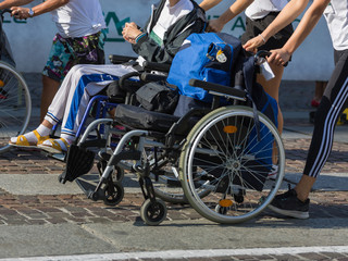 Fototapeta na wymiar Disabled Athlete in a Sport Wheelchair during Marathon Helped by Female Runners