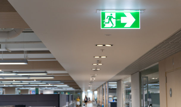 Green Fire Escape Sign Hang On The Ceiling In The Office.