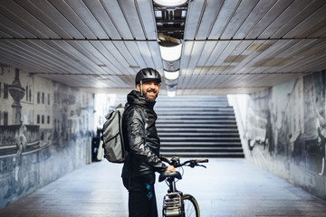 Male bicycle courier standing in subway when delivering packages in city.