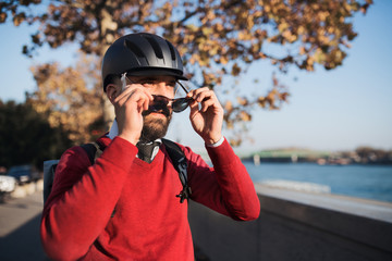 Businessman commuter with bicycle helmet and sunglasses on the way to work in city.