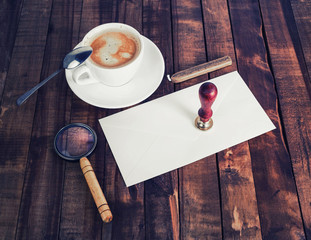 Blank retro stationery set on wood table background. Envelope, magnifier, coffee cup, stamp and...