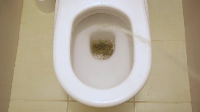 Man peeing to toilet bowl in restroom. Stream of urine flows into the bowl