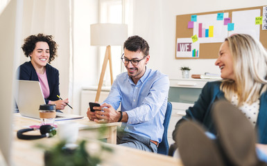 Group of young businesspeople with smartphone working together in a modern office.