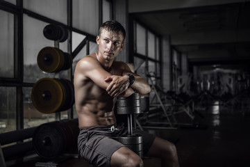 Fototapeta na wymiar Fitness guy holding huge dumbbell in old rusty gym. Shallow depth of field