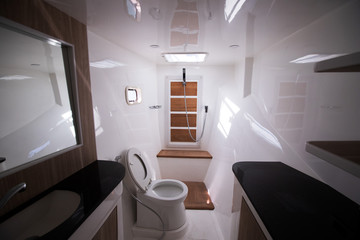 White Toilet restroom inside Yacht cruise with Windows sun ray, wash sink bath with shower in bathroom wc on ocean boat comfortable for all sailors and passenger during travel