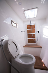 White Toilet restroom inside Yacht cruise with Windows sun ray, wash sink bath with shower in...