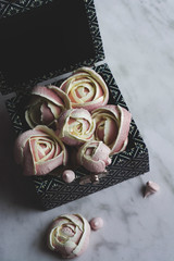 Soft pink meringues, shaped like roses in a blue box,  appetizing for valentine's day.