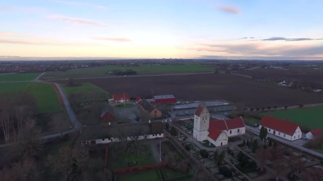 Aerial footage when flying over and mediaeval church and open fields in Sweden.