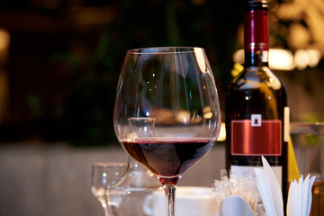 A glass of red wine on a served table in a restaurant.