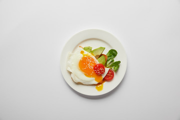 top view of scrambled egg with cherry tomato and avocado in plate on grey background