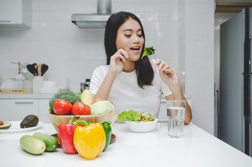 beautiful young asian woman slim body in white shirt dieting and eating healthy food, fresh vegetable salad sitting in kitchen interior in house, lifestyle, good healthy, diet food and drink concept