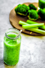 Green vegetable smoothie in glass at gray background