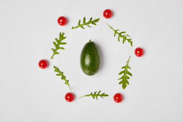 top view of avocado, arugulas leaves and cherry tomatoes on grey background