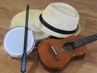 A samba player (sambista) hat and three Brazilian musical instruments: cavaquinho, pandeiro (tambourine) and tamborim with drumstick. They are widely used to accompany samba music.