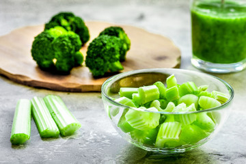 Green vegetable smoothie in glass at gray background
