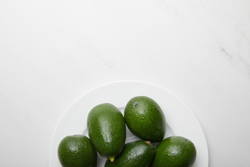 top view of avocados in plate on grey textured background