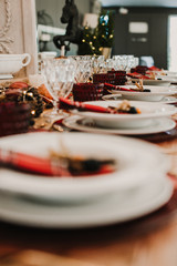 .Detail photograph of a table prepared and decorated for a party diner. Autumnal and festive decoration, with wood pineapples, candles, fruits and red colors. Lifestyle. Food photography