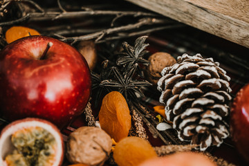 .Detail photograph of a table prepared and decorated for a party diner. Autumnal and festive decoration, with wood pineapples, candles, fruits and red colors. Lifestyle. Food photography