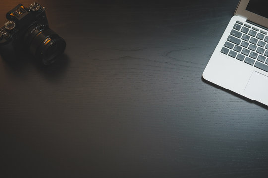 Laptop and old camera on dark wooden desk