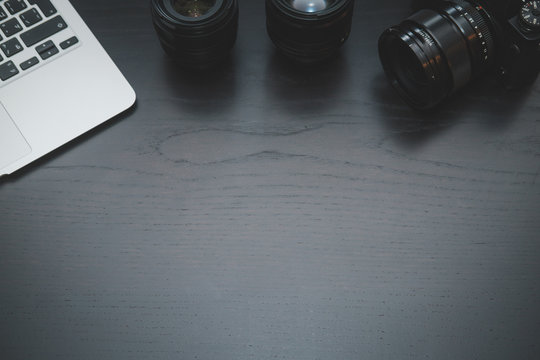 MacBook Air, camera and lenses on dark wooden desk