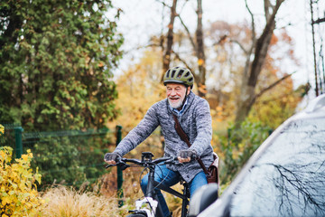 Active senior man with electrobike cycling outdoors in park.