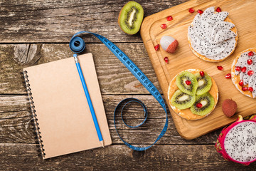Healthy lifestyle diet nutrition concept. Healthy snack from rice cakes with fruits. Notebook, pencil, measuring tape on wooden background. Diet, healthy lifestyle and fitness concept. To do list.