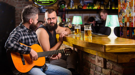 Man play guitar in bar. Cheerful friends relax with guitar music. Friday relaxation in bar. Friends relaxing in bar or pub. Real men leisure. Hipster brutal bearded spend leisure with friend in bar