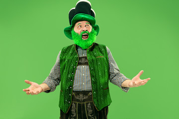 A smiling surprised happy senior man in a leprechaun hat with beard at green studio. He celebrates...