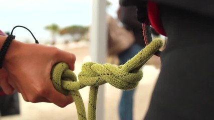 Woman preparing a friend for rappelling by tying a double figure eight climbing knot.
