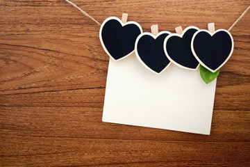 Heart shape chalkboards, blackboard with blank card clipped with Hemd rope on wooden background.