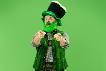 A smiling surprised happy senior man in a leprechaun hat with beard at green studio. He celebrates...