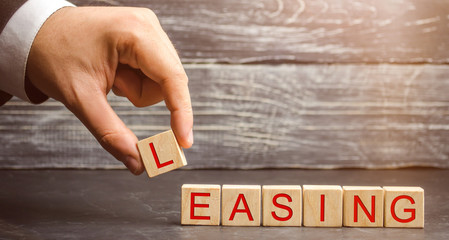Man puts cubes with the word Leasing. A lease is a contractual arrangement calling for the lessee to pay the lessor for use of an asset. Property, buildings, vehicles are common assets that are leased - obrazy, fototapety, plakaty